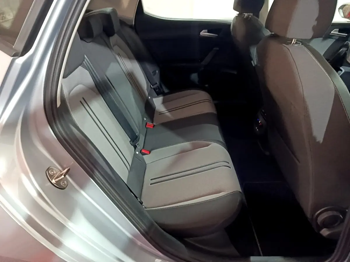 Vue intérieure côté arrière gauche montrant la banquette grise et les sièges avant du SEAT LEON gris clair 2023.