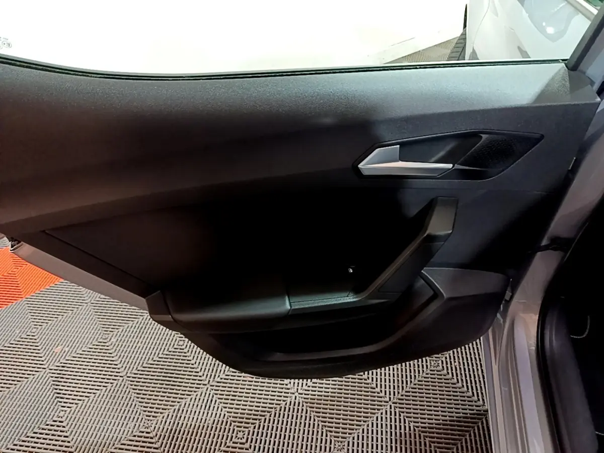 Vue rapprochée de la porte côté gauche gris clair d'une SEAT LEON 2023 avec poignée argentée et garniture noire.