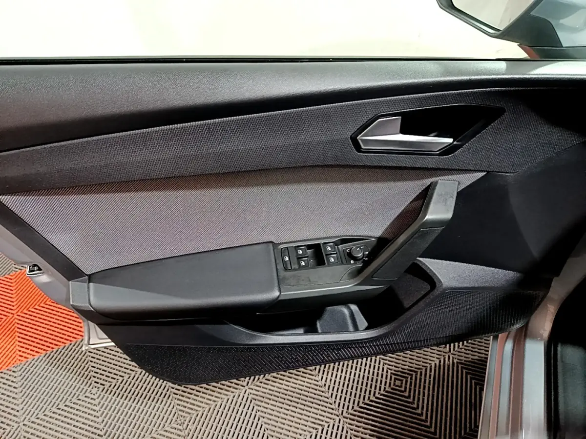 Vue rapprochée de la porte côté conducteur de la SEAT LEON gris clair, avec commandes des vitres et poignée noire.