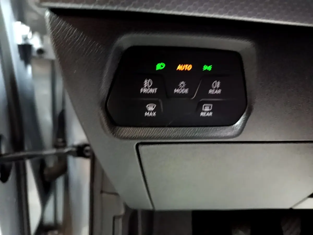 Panneau de commandes d'éclairage avec voyants verts et orange dans l'habitacle d'une SEAT Leon gris clair.