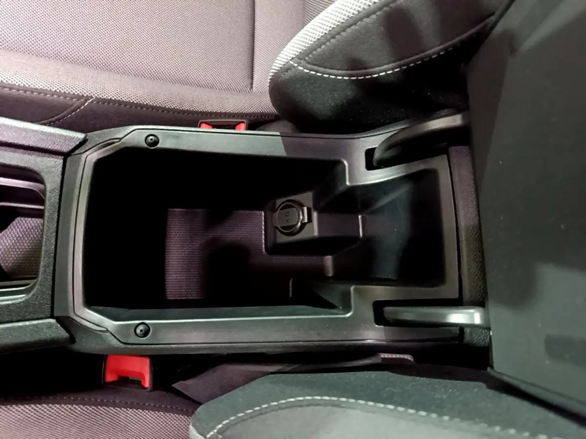 Vue plongeante sur le rangement central noir entre les sièges avant du SEAT Leon gris clair 2023.