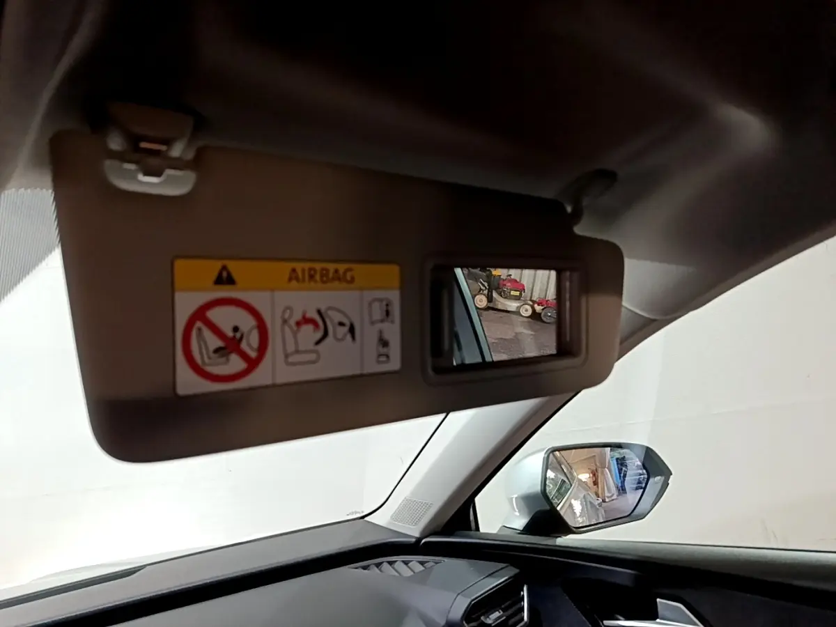 Détail du pare-soleil côté conducteur avec miroir intégré et rétroviseur extérieur gris clair d'une SEAT Leon 2023.