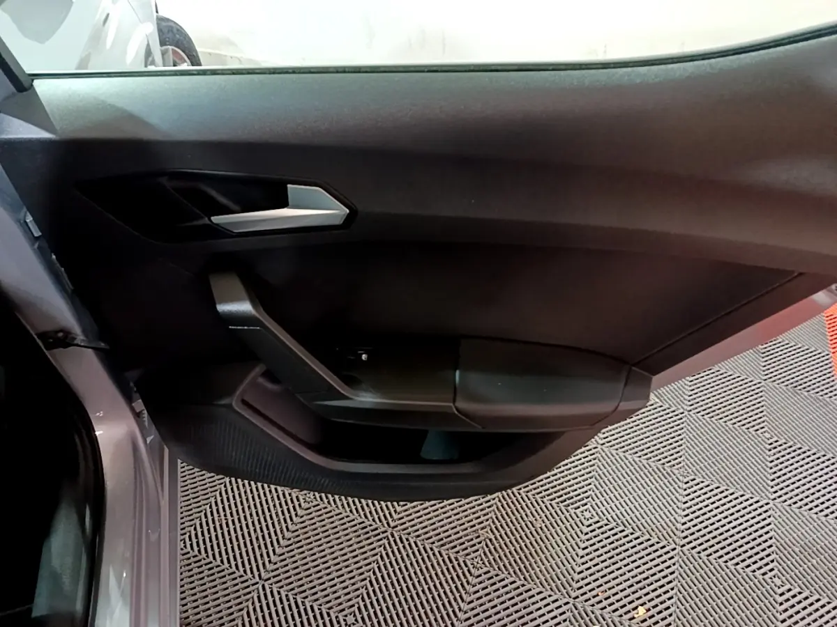 Vue rapprochée de la porte côté gauche gris clair du SEAT LEON 2023 avec poignée argentée et panneau noir mat.