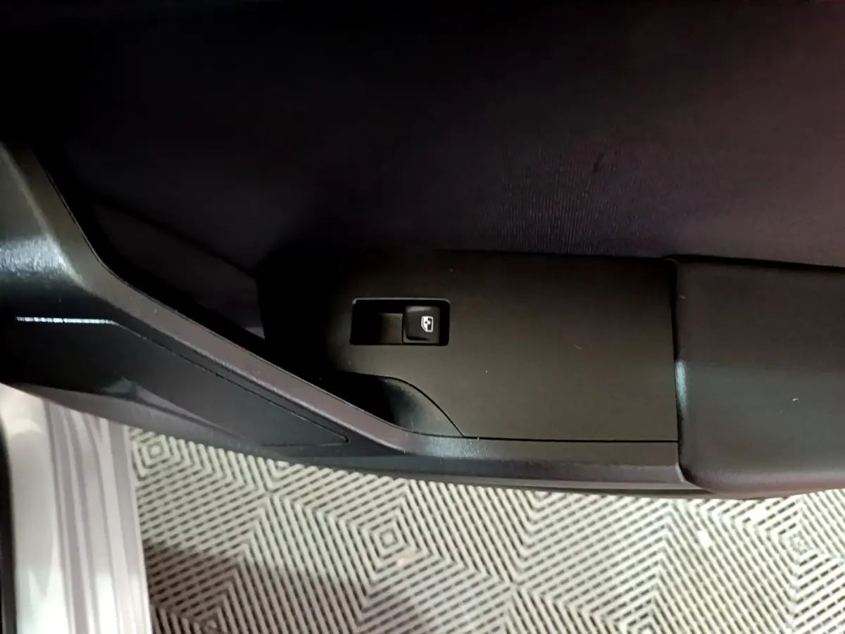 Bouton d'ouverture du coffre sur la porte côté gauche d'une SEAT Leon gris clair 2023.
