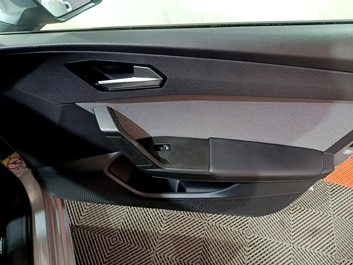 Panneau de porte côté gauche gris et noir de la SEAT LEON 2023 avec poignée argentée et bouton de vitre électrique.