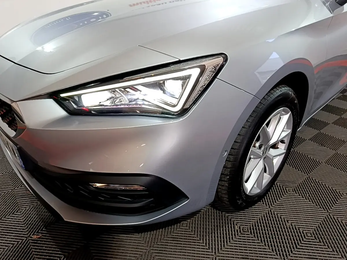 Gros plan sur l'avant droit gris clair du SEAT LEON 2023, mettant en valeur le phare LED et la jante alliage.