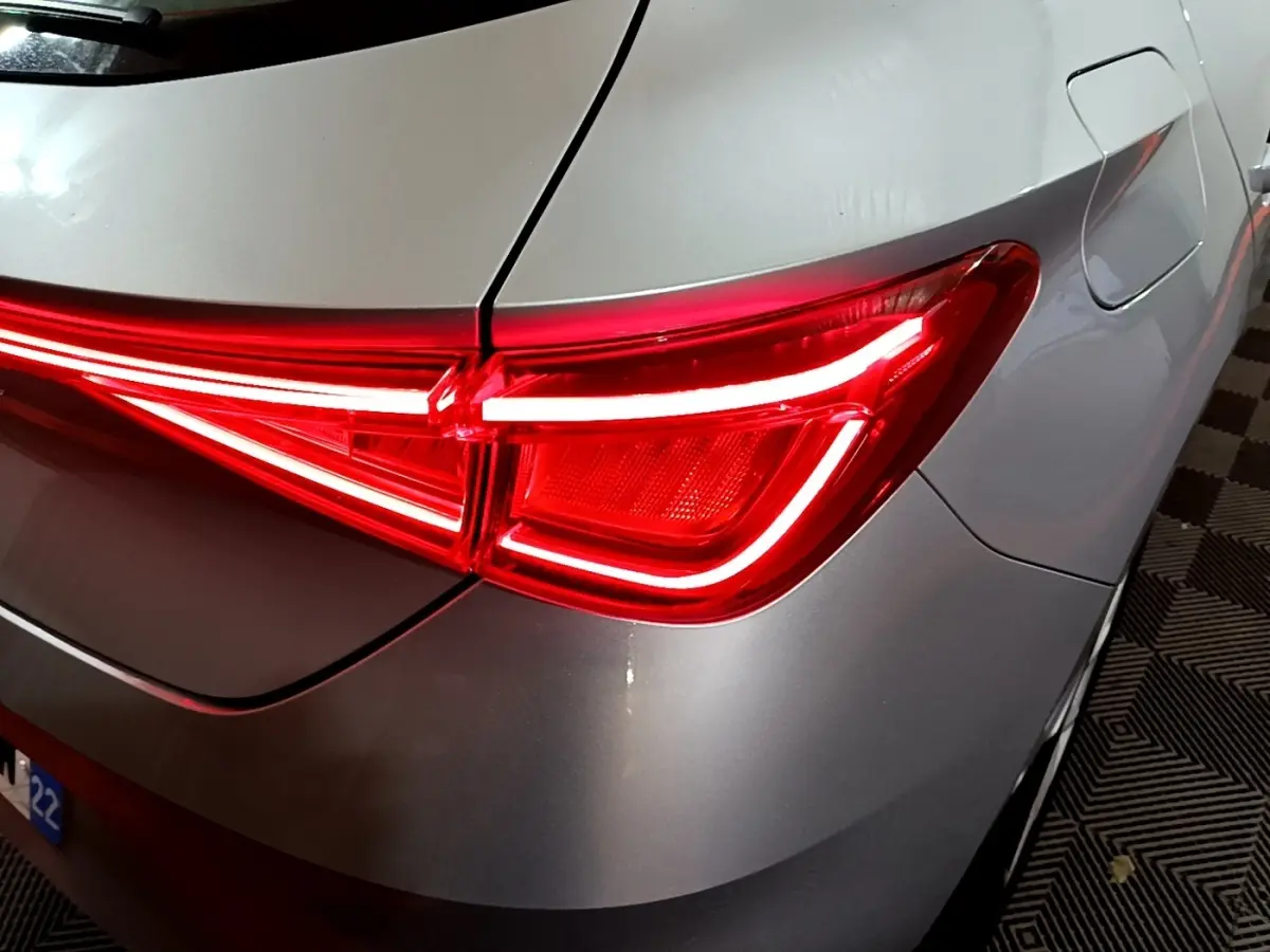 Gros plan sur le feu arrière droit rouge allumé d'une SEAT LEON gris clair 2023, avec la trappe à carburant visible.