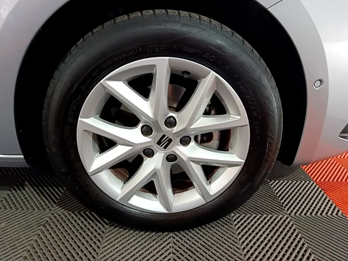 Gros plan sur la jante alliage argentée côté avant droit d'une SEAT LEON gris clair 2023 avec logo central visible.