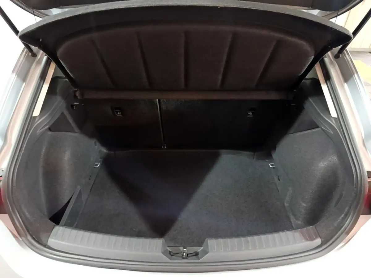 Coffre ouvert vu de l'arrière d'une SEAT LEON gris clair 2023, espace de chargement vide et tapis noir.