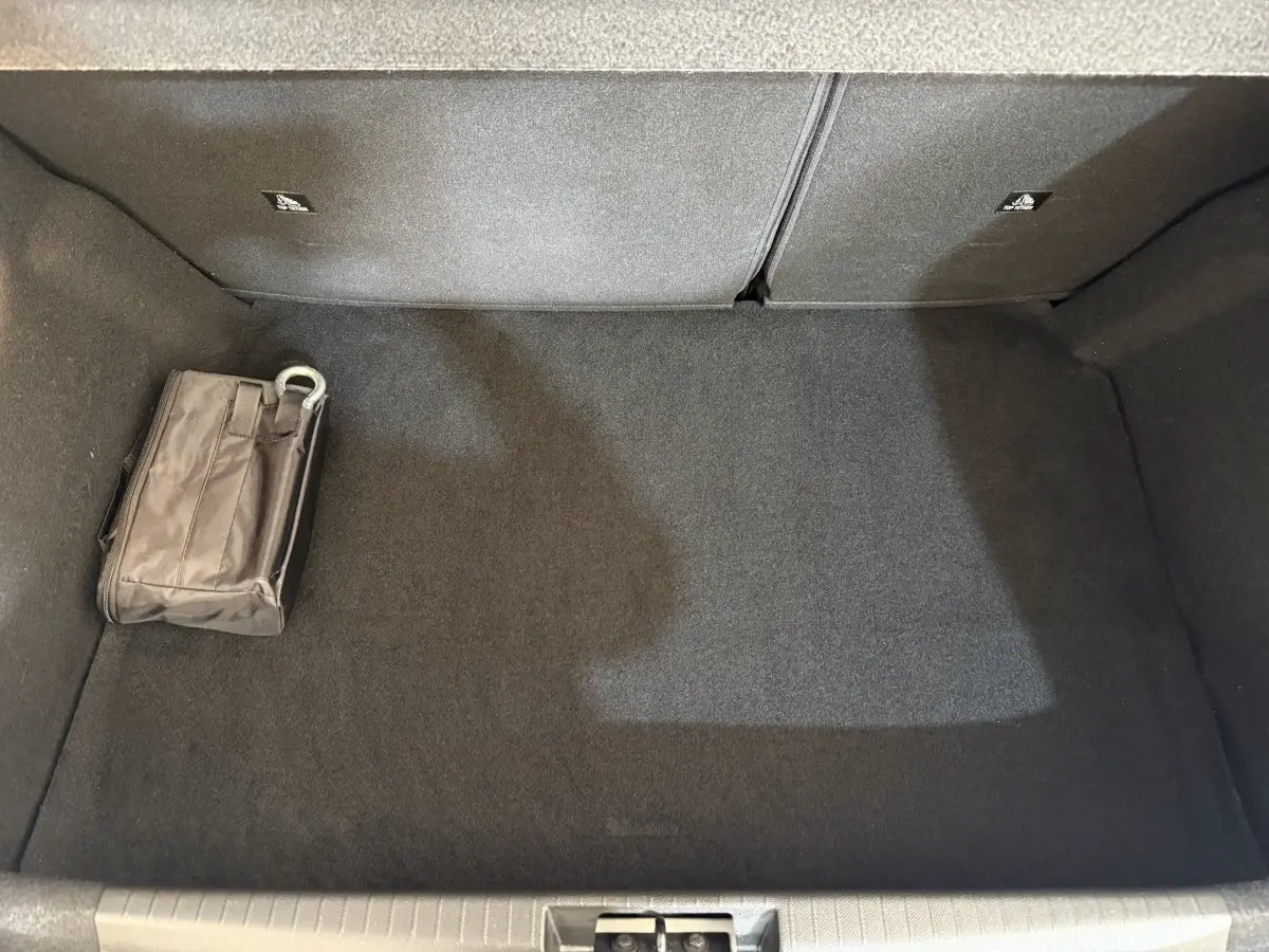 Vue plongeante sur le coffre gris foncé de la Peugeot 208 PureTech 75 avec une trousse de secours posée à gauche.