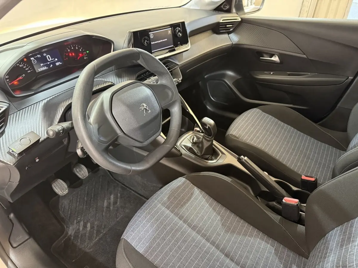 Vue intérieure côté conducteur de la Peugeot 208 PureTech 75 S&S Like 2020 avec sièges gris et volant compact noir.