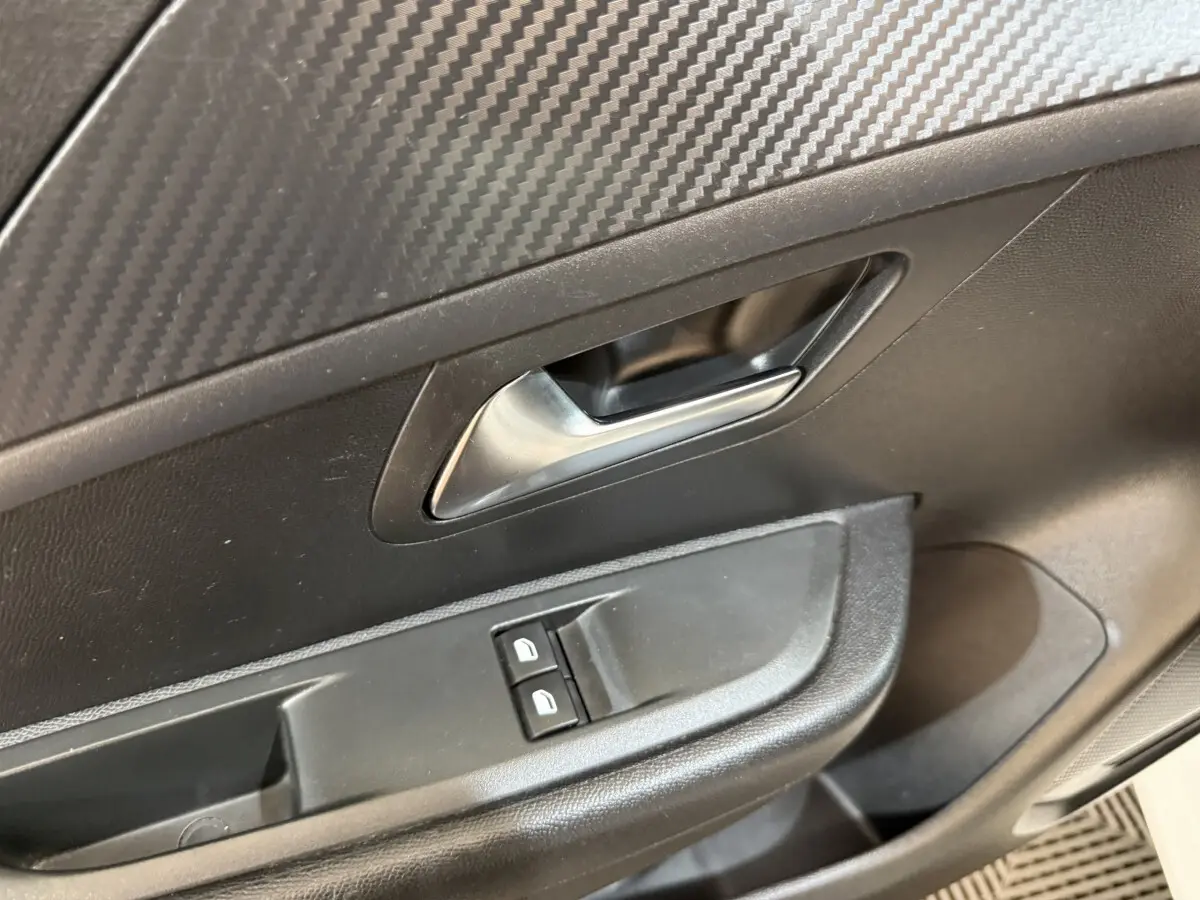 Détail de la poignée intérieure et des commandes de lève-vitres côté conducteur d’une Peugeot 208 PureTech 75 S&S Like 2020.