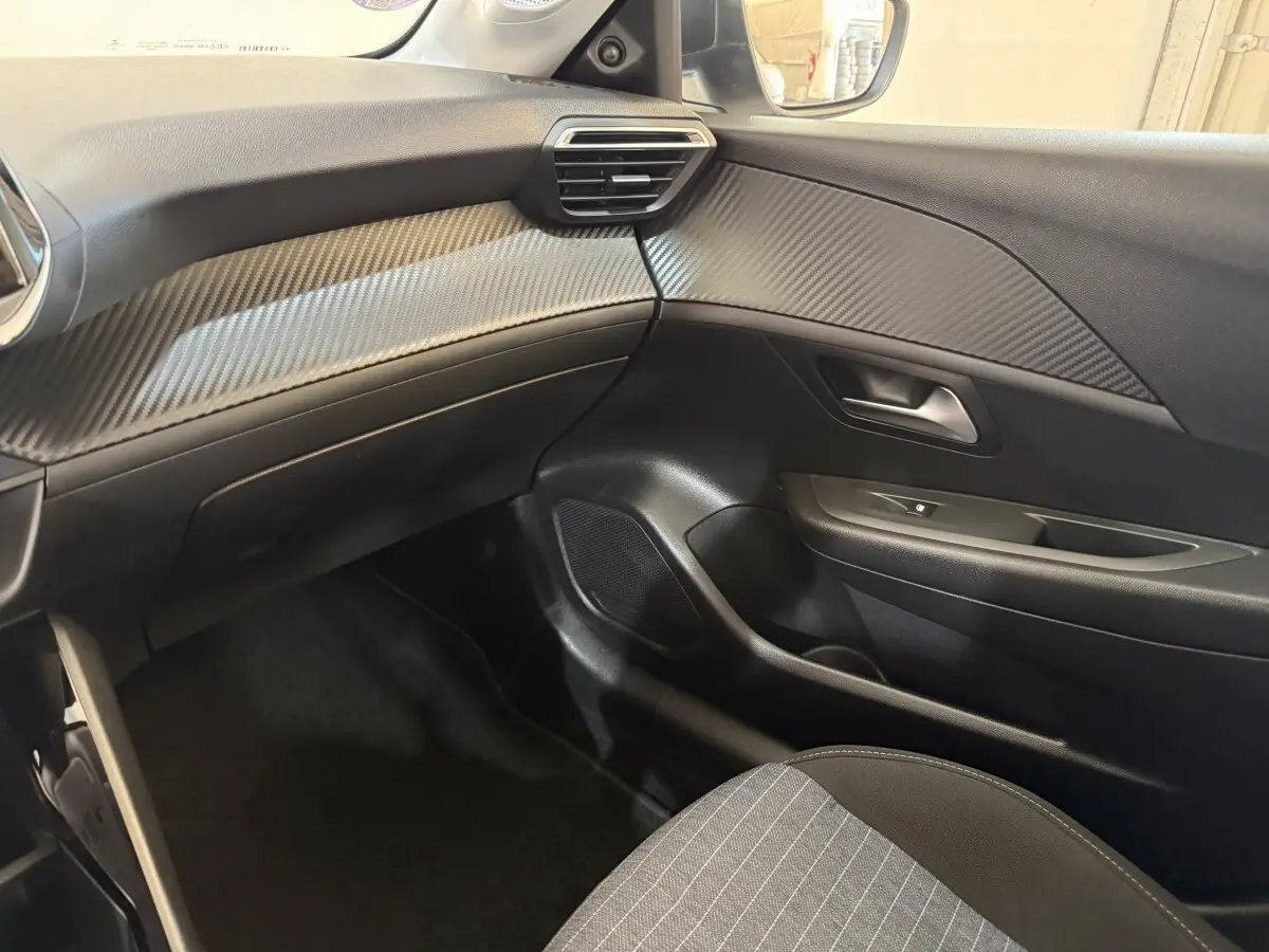 Intérieur côté passager de la Peugeot 208 PureTech 75 S&S Like 2020, avec tableau de bord noir et inserts effet carbone.