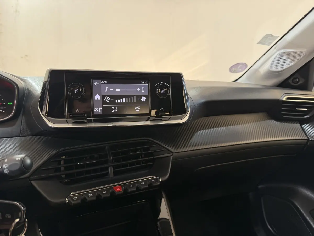 Vue intérieure du tableau de bord noir de la Peugeot 208 PureTech 75 S&S Like avec écran tactile central et commandes climatisation.