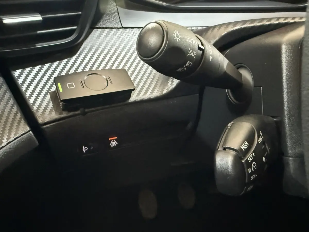 Gros plan sur la commande des feux et régulateur de vitesse du tableau de bord noir à effet carbone d'une Peugeot 208 2020.