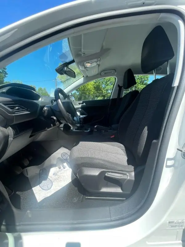 Vue intérieure côté conducteur de la Peugeot 308 blanche 2020, montrant les sièges avant et le tableau de bord.