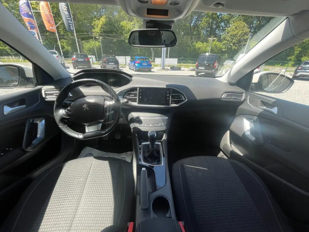 Vue intérieure avant du Peugeot 308 blanc 2020, montrant le volant, tableau de bord et levier de vitesse manuel.