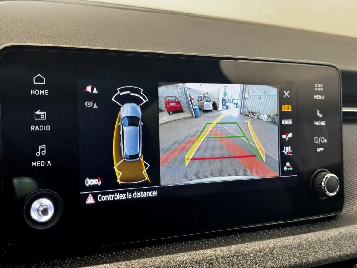 Écran tactile intérieur montrant la caméra de recul et l'aide au stationnement du Skoda Scala gris clair.