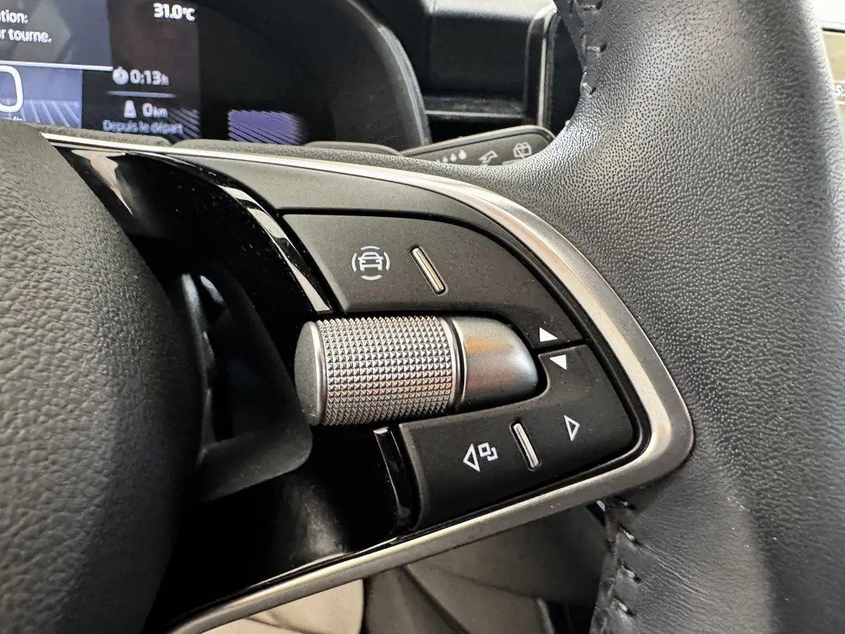 Gros plan sur les commandes multifonctions en alu et cuir du volant noir d'une Skoda Scala gris clair, version 2025.