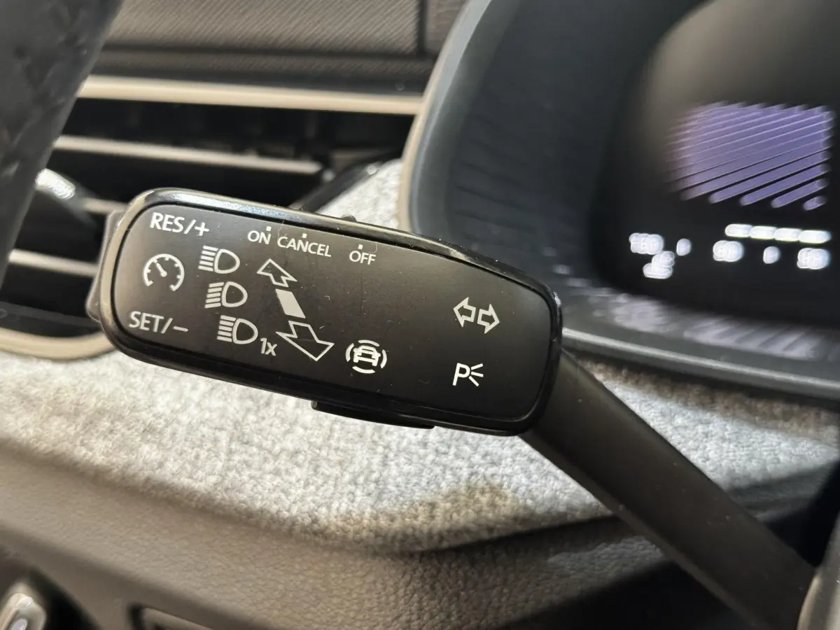 Gros plan sur la commande de régulateur de vitesse et feux, intérieur d'une Skoda Scala gris clair 2025.