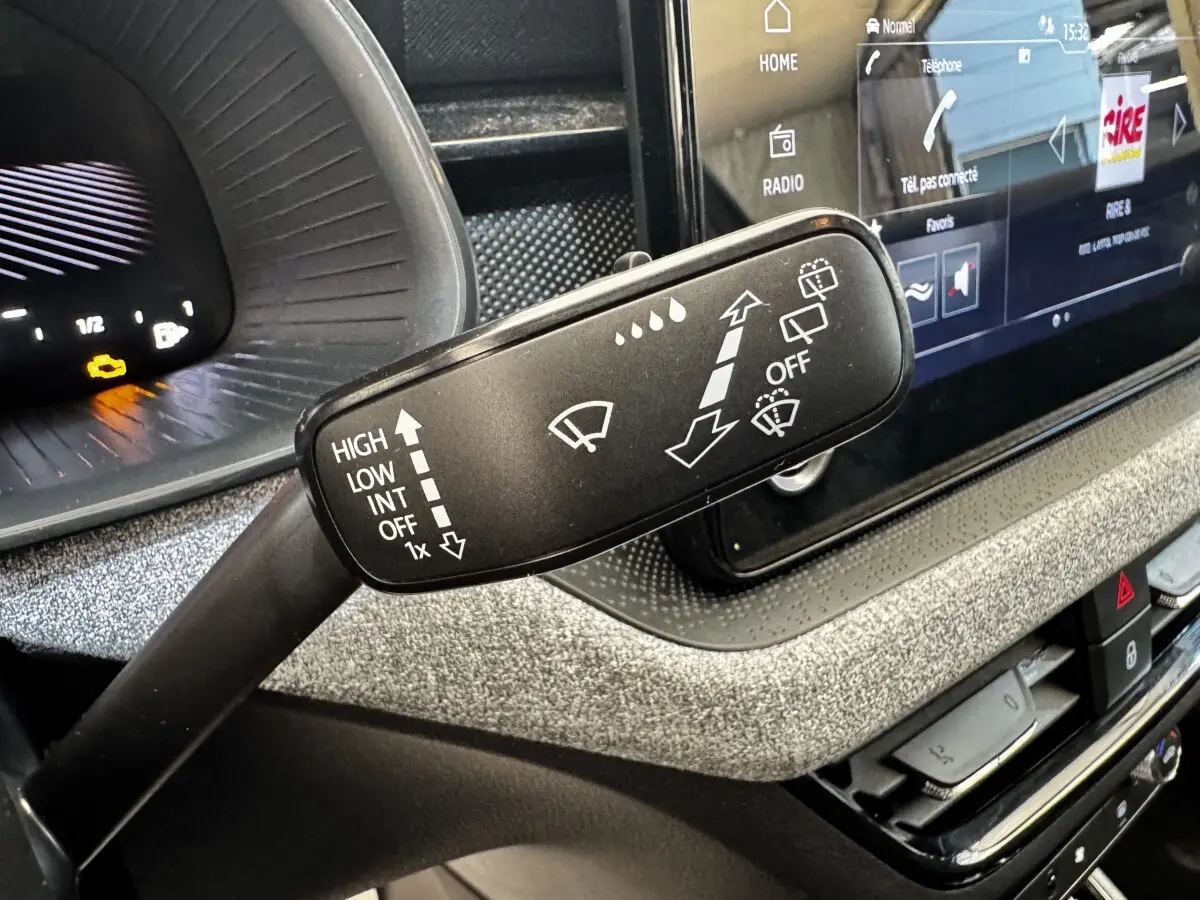 Gros plan sur la commande des essuie-glaces dans l’habitacle gris clair du Skoda Scala 2025, avec écran tactile en arrière-plan.