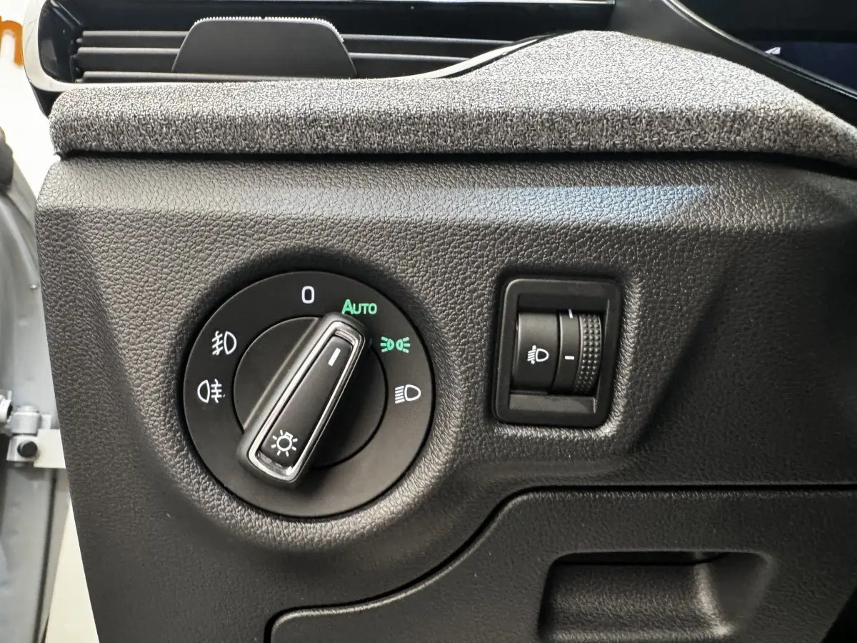 Gros plan sur la commande des phares avec réglage d'intensité dans une Skoda Scala gris clair, intérieur noir texturé.