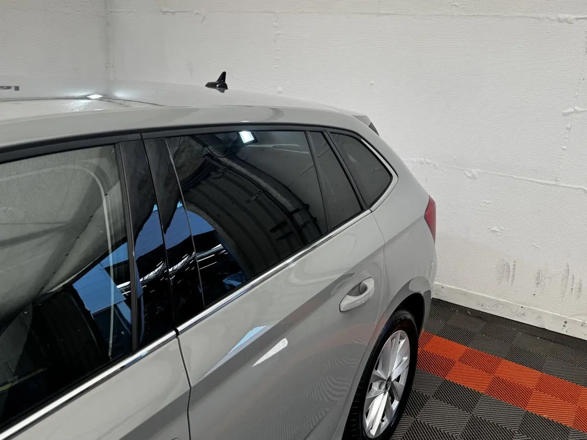Vue 3/4 arrière côté droit d'une Skoda Scala gris clair avec vitres teintées et jantes alliage dans un garage.