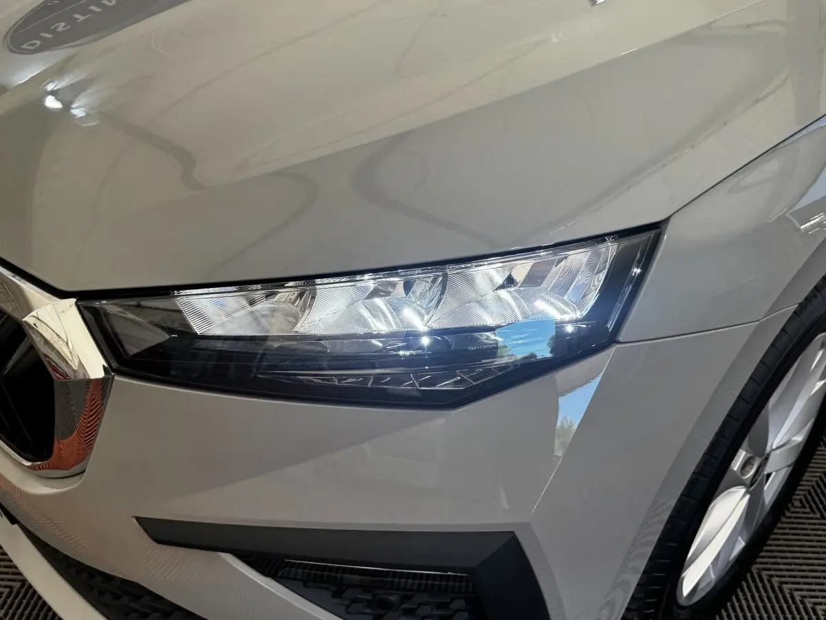 Gros plan sur le phare avant droit gris clair d'une Skoda Scala 2025, mettant en valeur les lignes nettes et la calandre chromée.