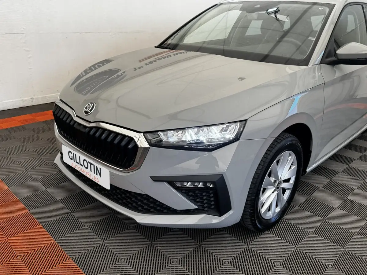 Vue 3/4 avant droite d'une Skoda Scala gris clair avec calandre noire et phares LED distinctifs.