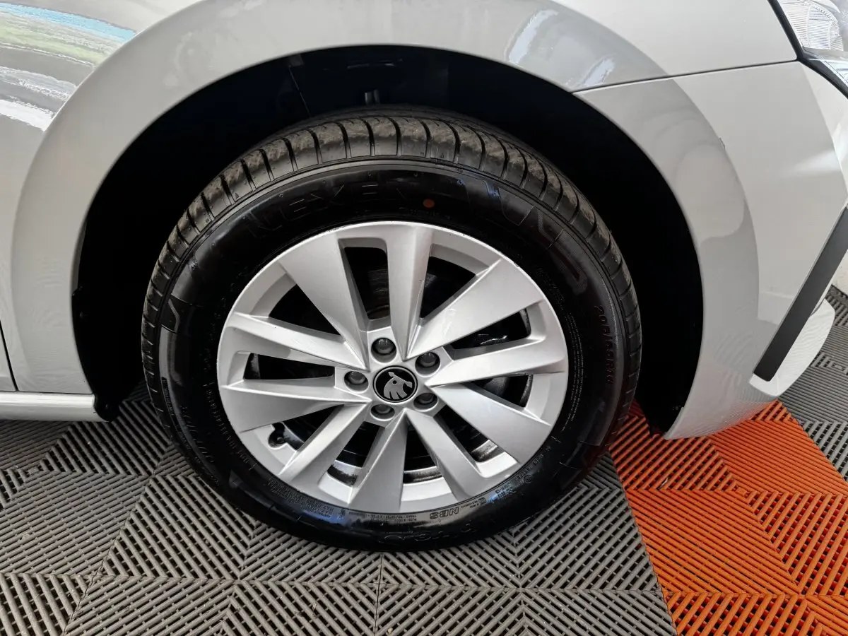 Gros plan sur la roue avant droite gris clair d'une Skoda Scala 2025 avec jante alliage et logo central visible.