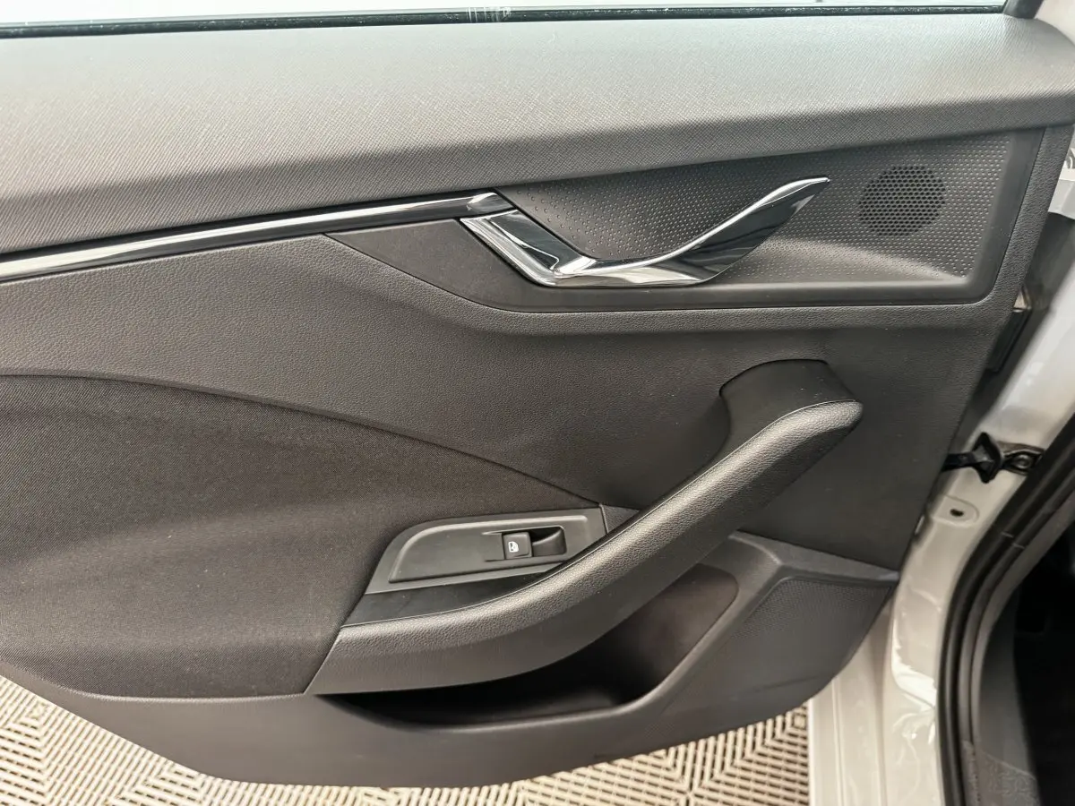 Vue intérieure de la porte avant droite d'une Skoda Scala gris clair, avec poignée chromée et commande de verrouillage.