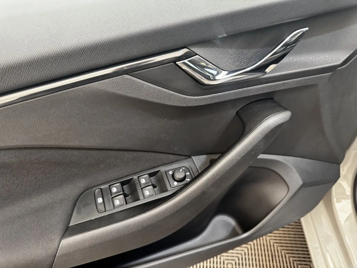 Vue rapprochée de la porte côté conducteur d'une Skoda Scala gris clair, avec commandes des vitres et miroir.