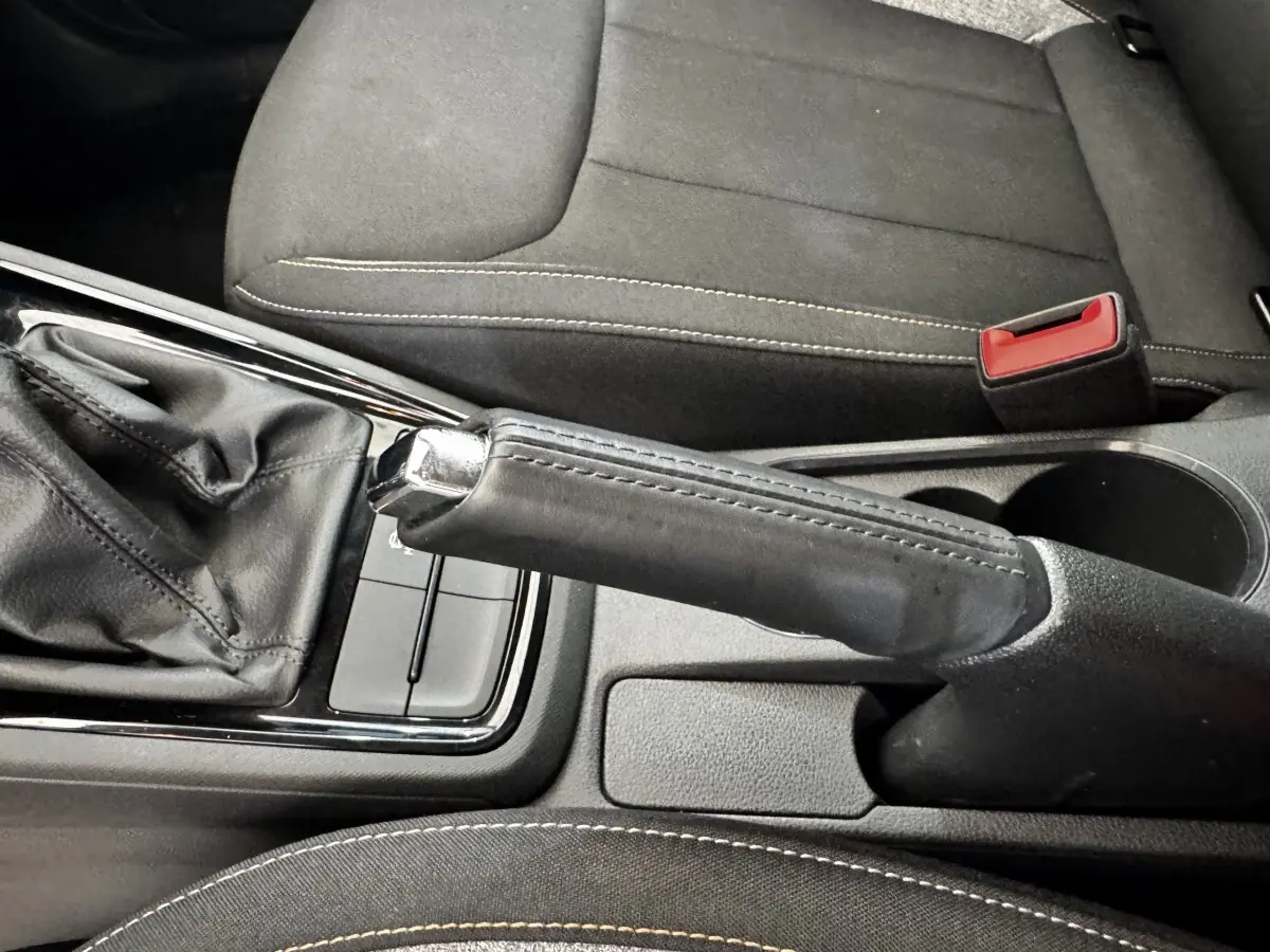 Gros plan intérieur sur le frein à main en cuir noir et la console centrale d’une Skoda Scala gris clair.