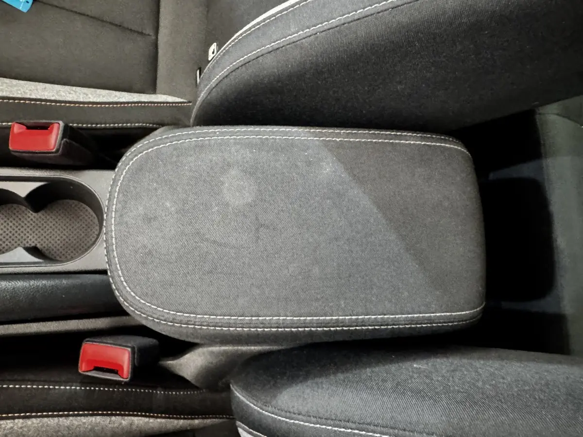 Vue rapprochée de l'accoudoir central gris foncé avec surpiqûres blanches et porte-gobelets d'une Skoda Scala 2025.