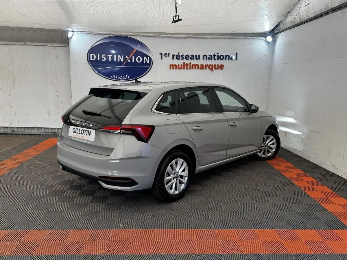 Vue 3/4 arrière droite d'une Skoda Scala gris clair dans un showroom avec feux arrière LED et jantes alliage.