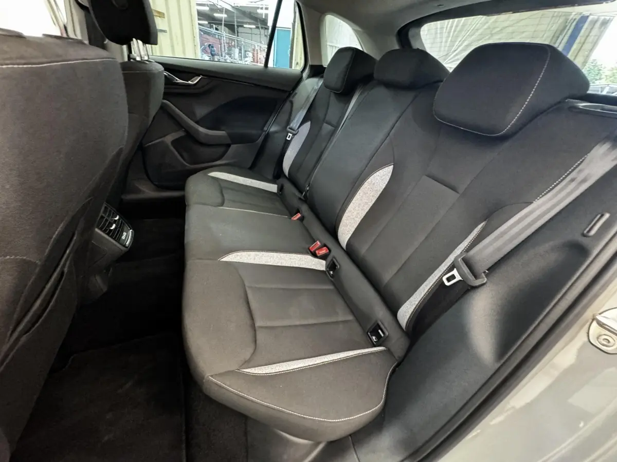 Vue intérieure arrière droite de la Skoda Scala 2025 gris clair, montrant la banquette tissu noire avec inserts gris clair.
