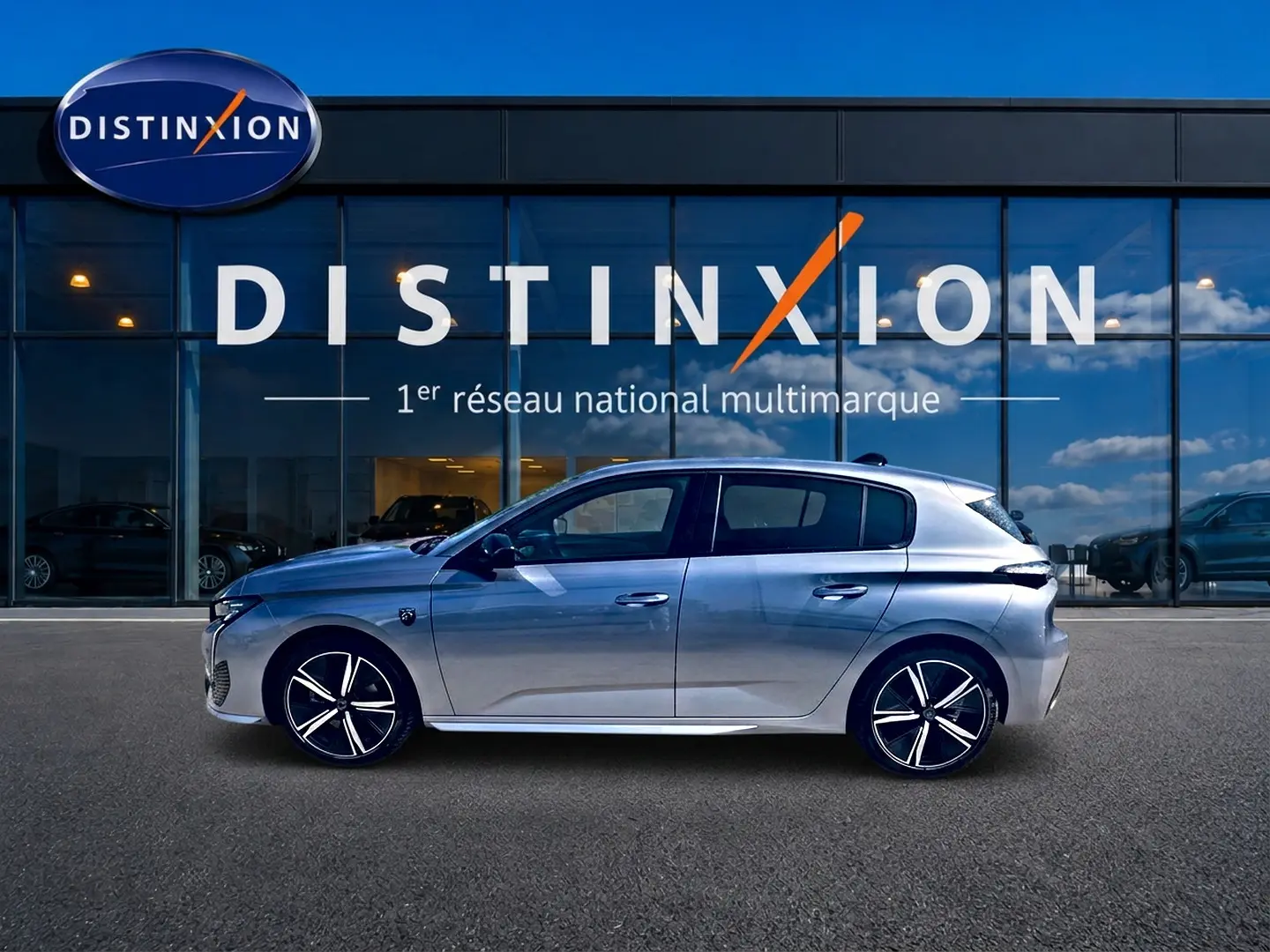 Peugeot 308 gris en profil droit, avec jantes alliage et toit légèrement incliné, devant une vitrine Distinxion.
