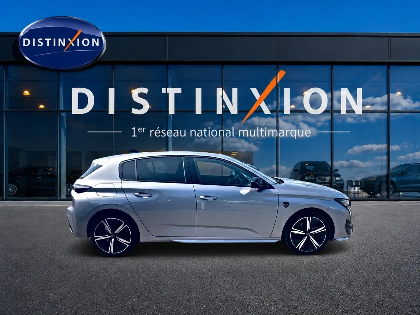 Peugeot 308 gris vue de profil côté gauche, avec jantes alliage distinctives, devant une vitrine Distinxion.