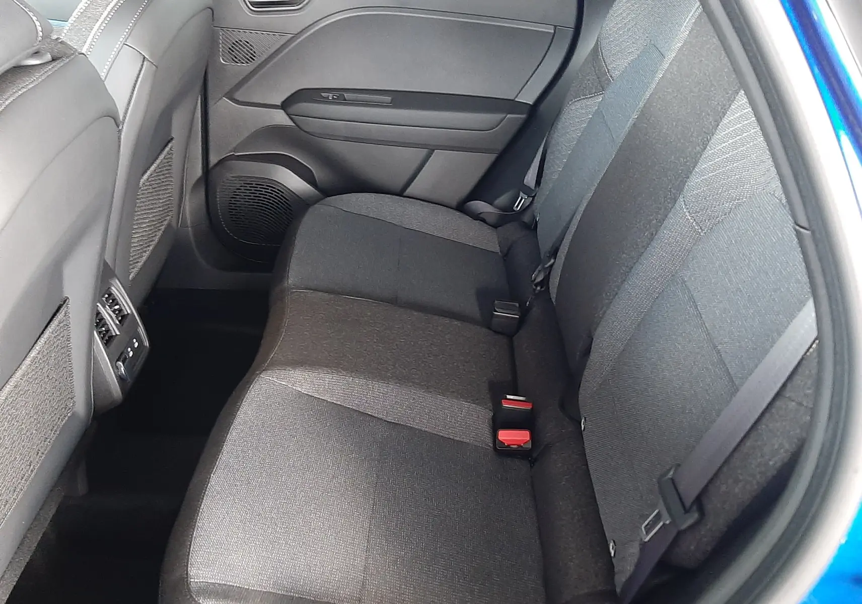 Vue intérieure côté droit des sièges arrière en tissu gris du Renault Captur E-Tech Hybrid 2024 bleu iron avec toit noir.