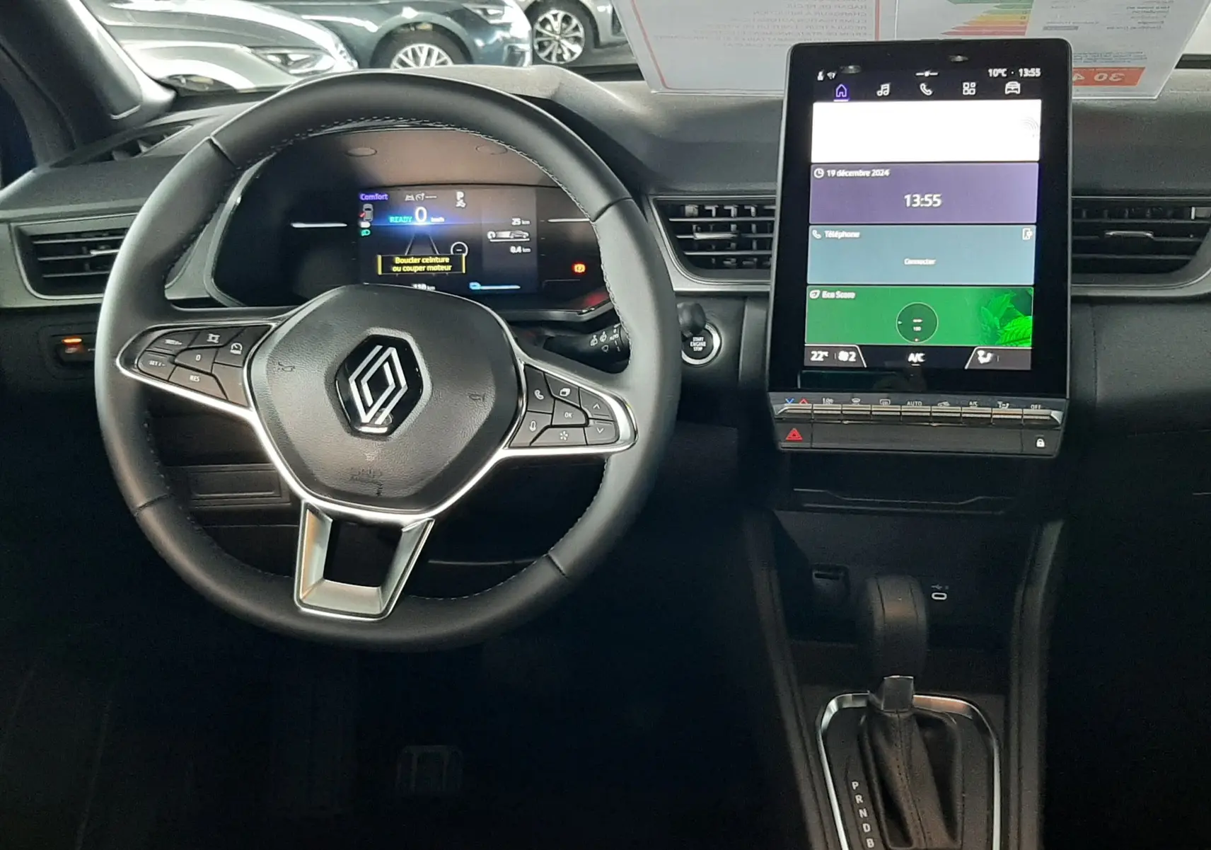 Vue intérieure du tableau de bord du Renault Captur E-Tech Hybrid 2024, avec volant multifonction et écran tactile vertical.