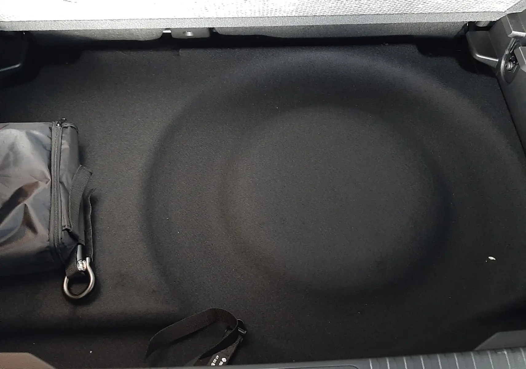 Coffre arrière du Renault Captur E-Tech Hybrid 2024, vue plongeante sur le rangement noir avec sac de secours.