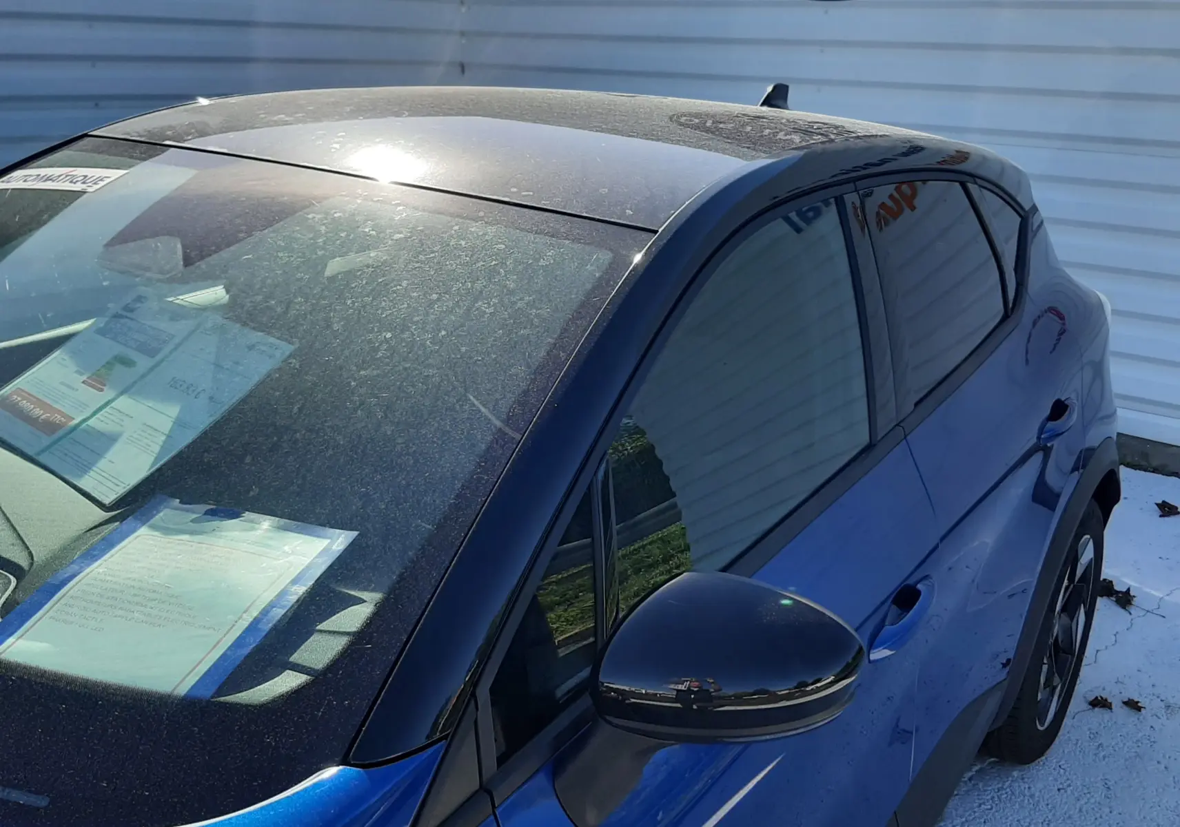 Vue 3/4 avant droit du Renault Captur E-Tech Hybrid 2024 bleu Iron avec toit noir et rétroviseur assorti.