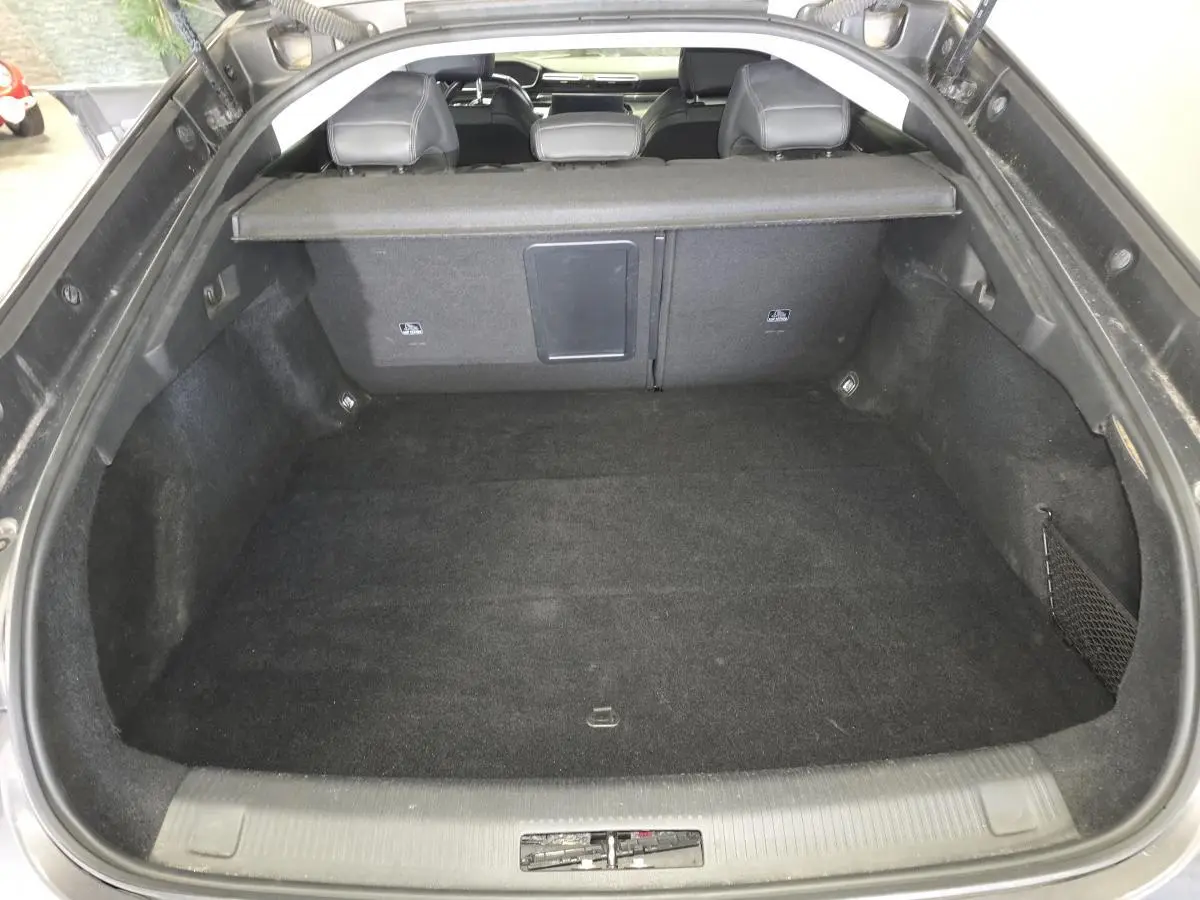 Coffre ouvert vu de l'arrière d'une Peugeot 508 gris, montrant l'espace de chargement et la banquette arrière.