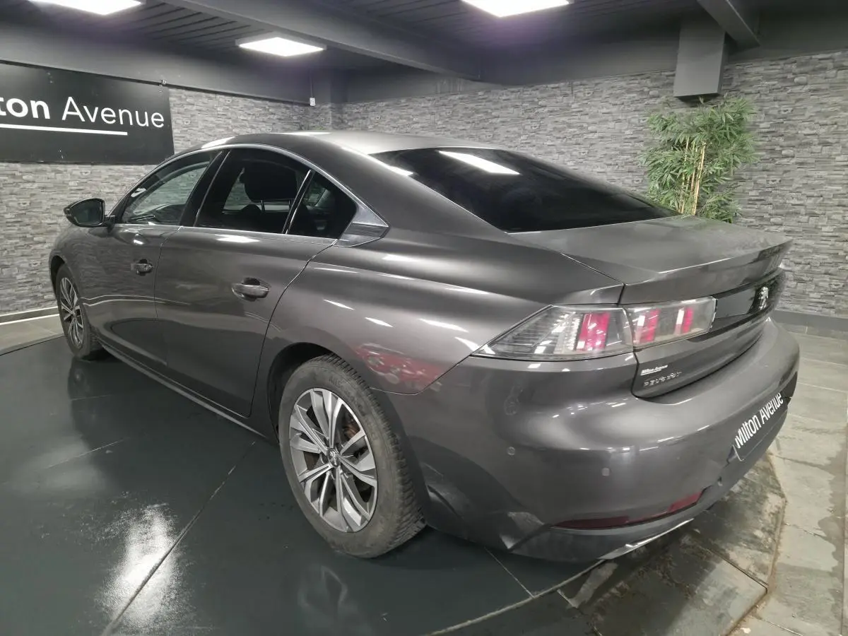 Peugeot 508 gris métallisé vue 3/4 arrière droit, avec feux arrière distinctifs et jantes alliage 17 pouces.