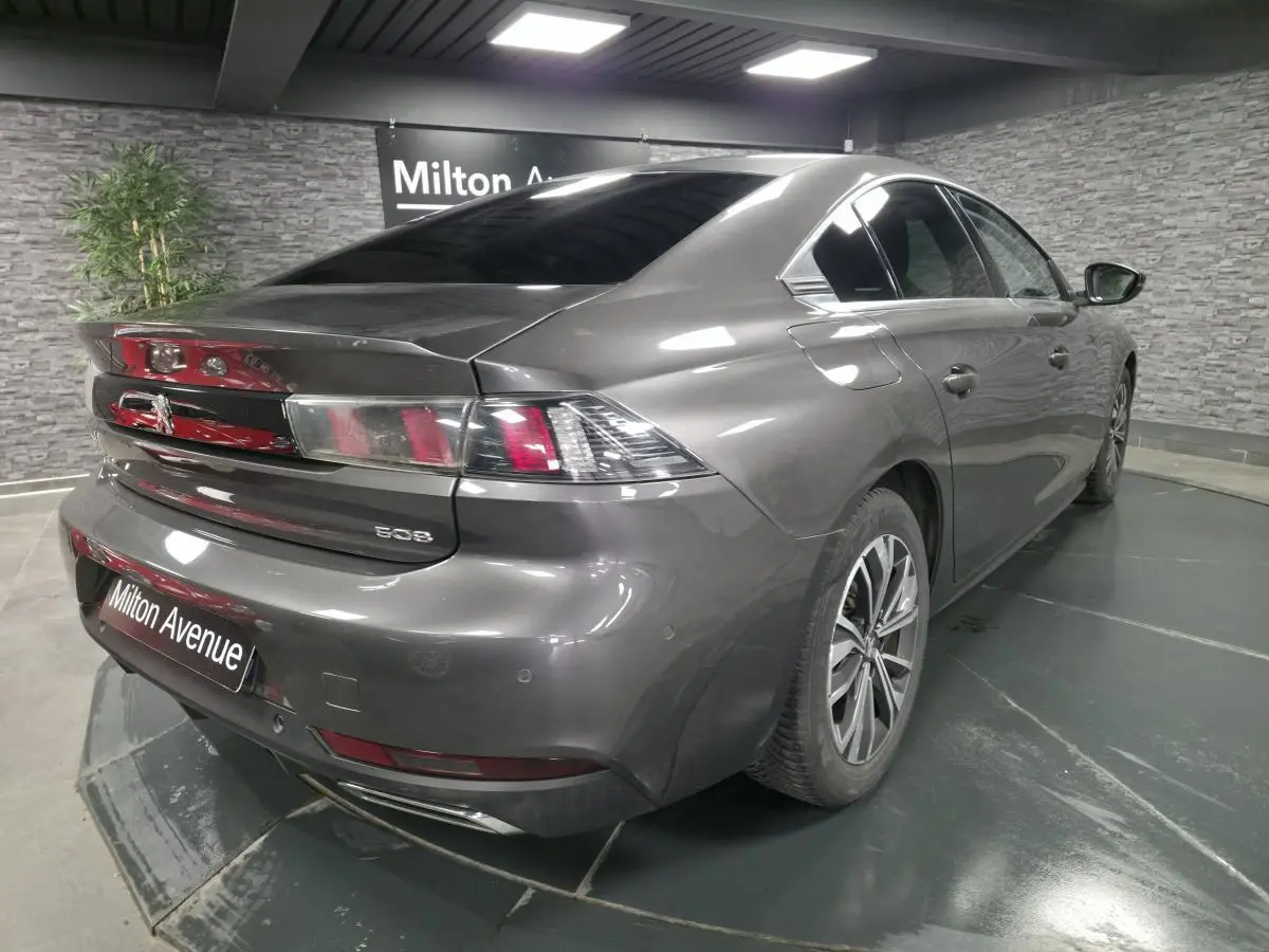 Peugeot 508 gris métallisé vue 3/4 arrière droit en intérieur avec jantes alliage et double échappement chromé.