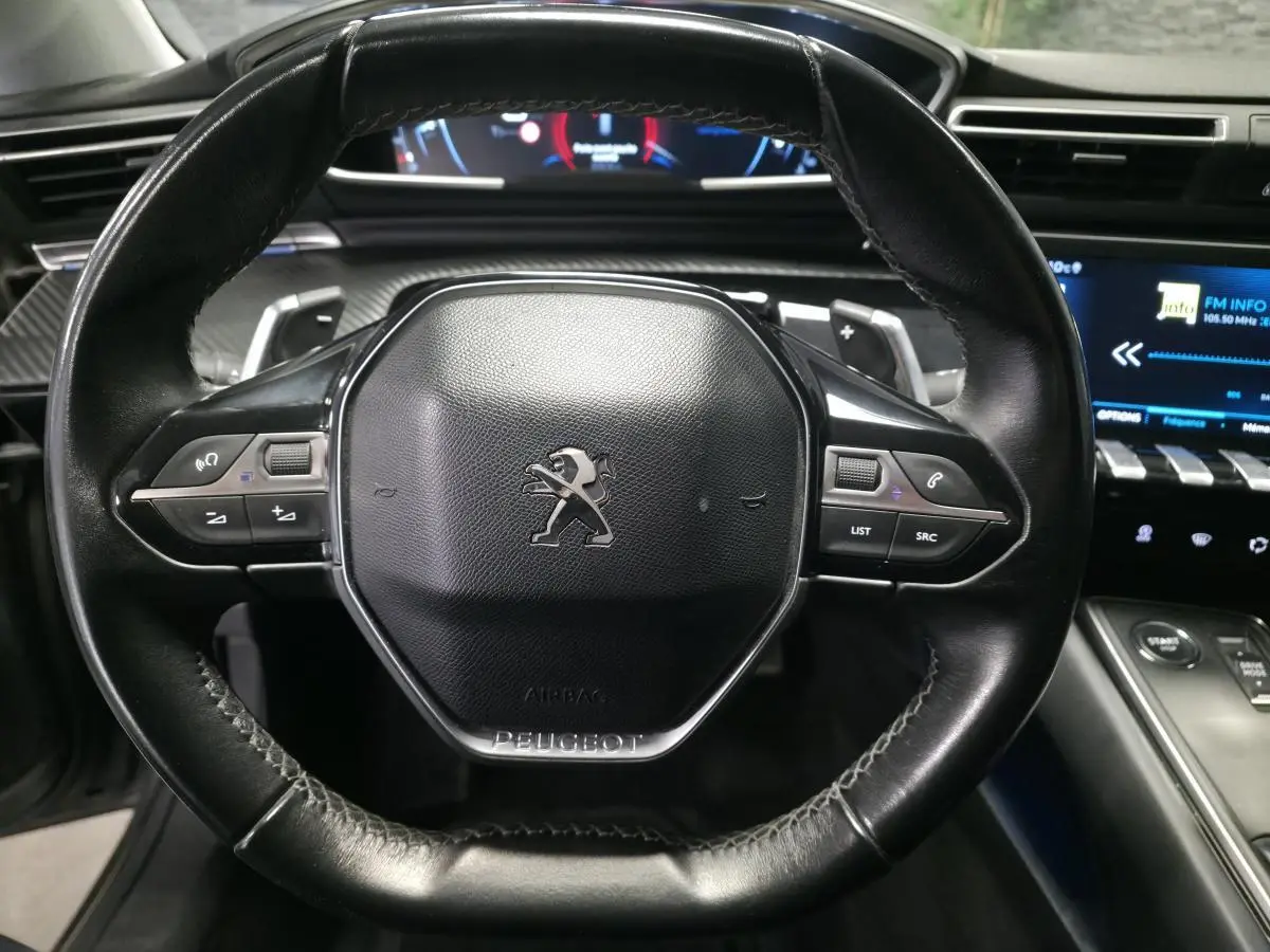 Volant cuir noir Peugeot 508 2018 avec commandes intégrées et tableau de bord numérique en arrière-plan.