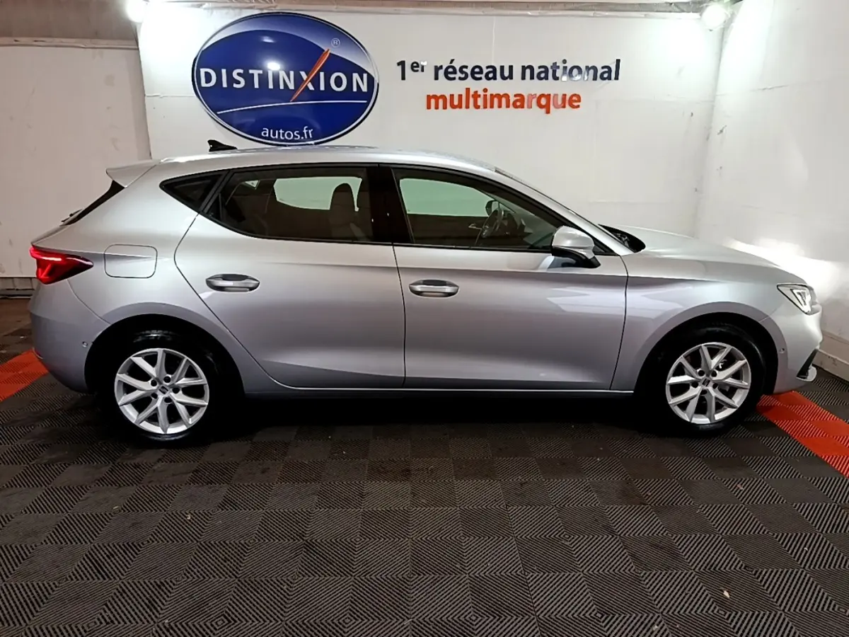 Profil côté gauche d'une SEAT Leon gris foncé 2023, en intérieur, avec jantes alliage et lignes épurées.