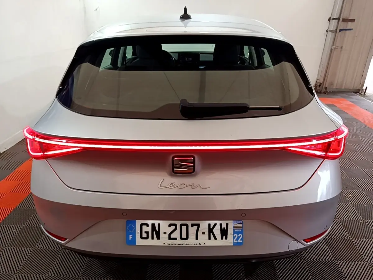 Vue arrière d'une SEAT Leon gris foncé 2023 avec feux LED allumés et plaque d'immatriculation française visible.