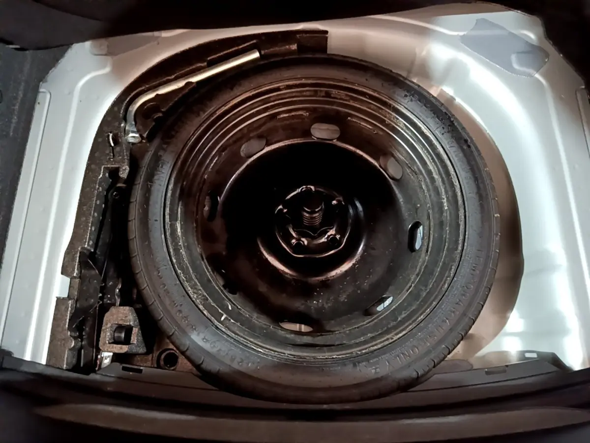 Roue de secours galette noire dans le coffre blanc d'une SEAT LEON 1.0 TSI 110 S&S Business 2023.