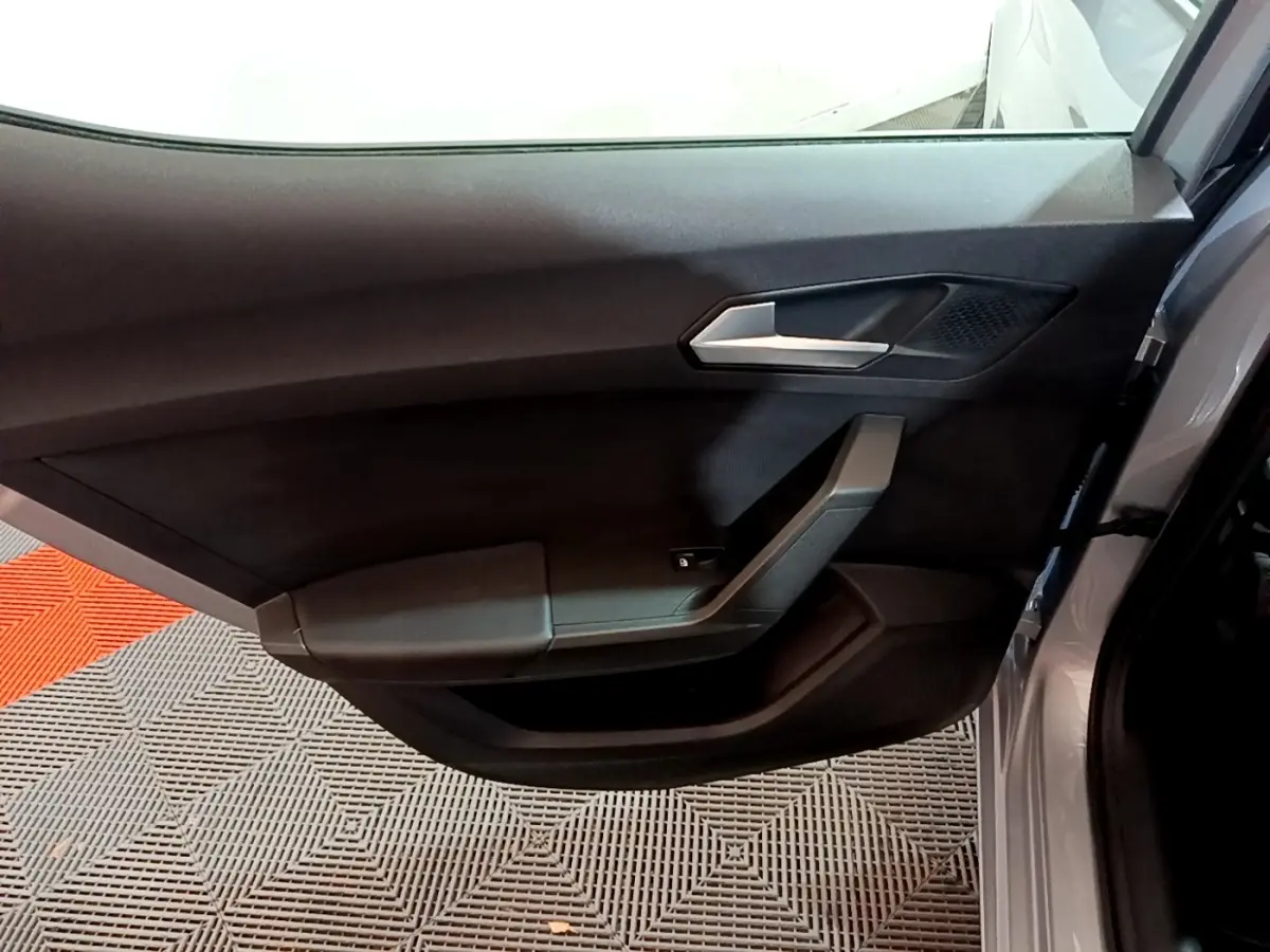 Vue rapprochée de la porte arrière droite gris foncé d'une SEAT LEON 2023 avec poignée argentée et accoudoir intégré.